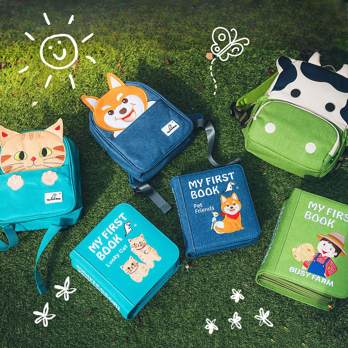 Mehrere My First Book Quiet Books mit Tier-Rucksäcken (Lucky Cat, Pet Friends, Bauernhof) auf einer Wiese – Montessori-Spielzeug für Kinder von 0 bis 6 Jahren
