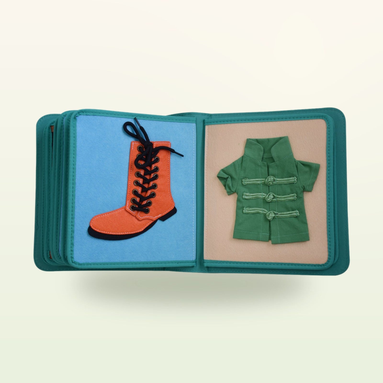 Kleiderschrank Quiet Book Stoffseite mit oranger Schnürstiefel und grüner Jacke mit Knebelknöpfen auf sanftem Creme-Hintergrund – ab 3 Jahren