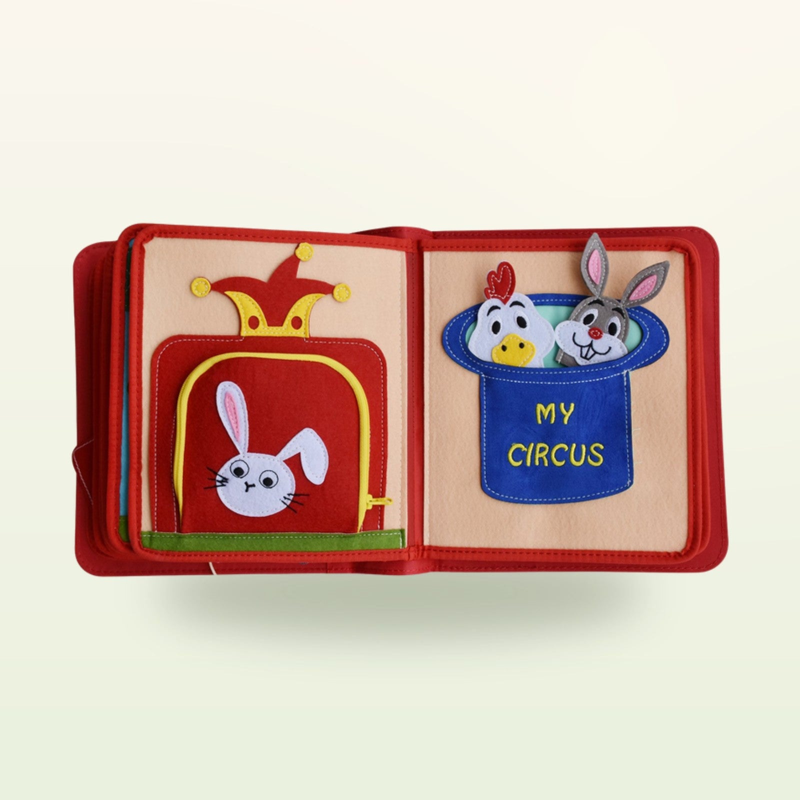 Zirkusabenteuer Quiet Book Zauberkasten-Doppelseite mit Kaninchen im Zylinder und My-Circus-Tasche mit Tier-Fingerpuppen auf sanftem cremefarbenem Hintergrund – ab 3 Jahren