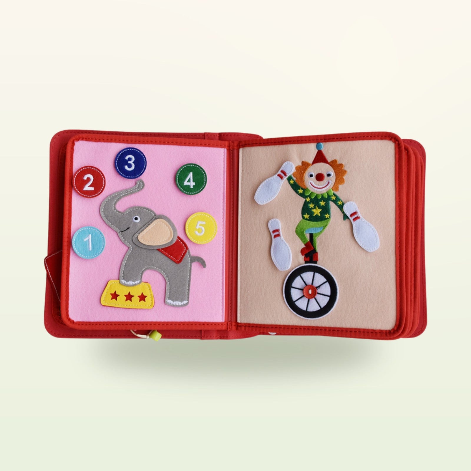 Zirkusabenteuer Quiet Book Zähl-Doppelseite mit Elefant mit Zahlenknöpfen 1 bis 5 und jonglierendem Clown auf dem Einrad auf sanftem cremefarbenem Hintergrund – ab 3 Jahren