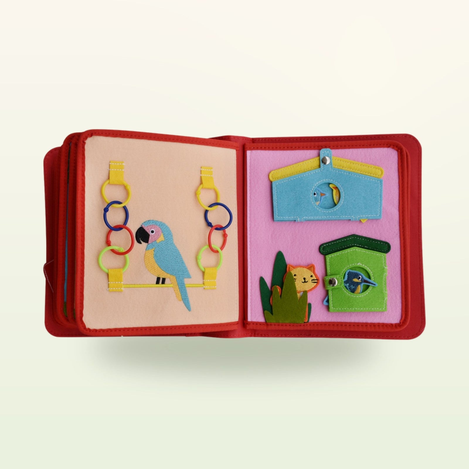 Zirkusabenteuer Quiet Book Vogel-Doppelseite mit Papagei mit Filzringen zum Auffädeln und Vogelhäuschen mit Druckknopf-Klappen auf sanftem cremefarbenem Hintergrund – ab 3 Jahren