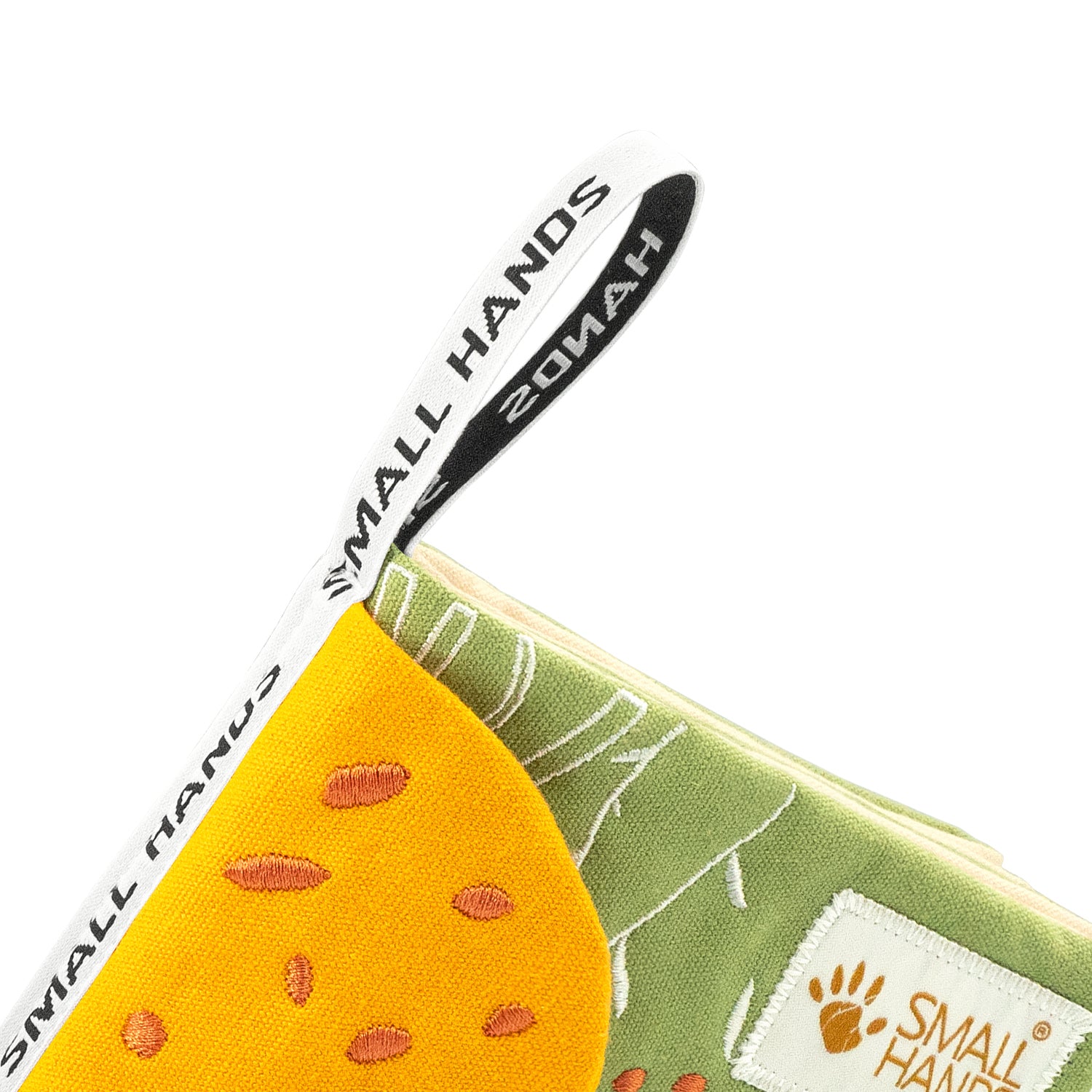 Tiere Afrikas Montessori Sensorik-Stoffbuch – Detailaufnahme der weißen Aufhängeschlaufe mit Small Hands Schriftzug an der Buchecke über der gelben Giraffe mit orangen Flecken, für Babys