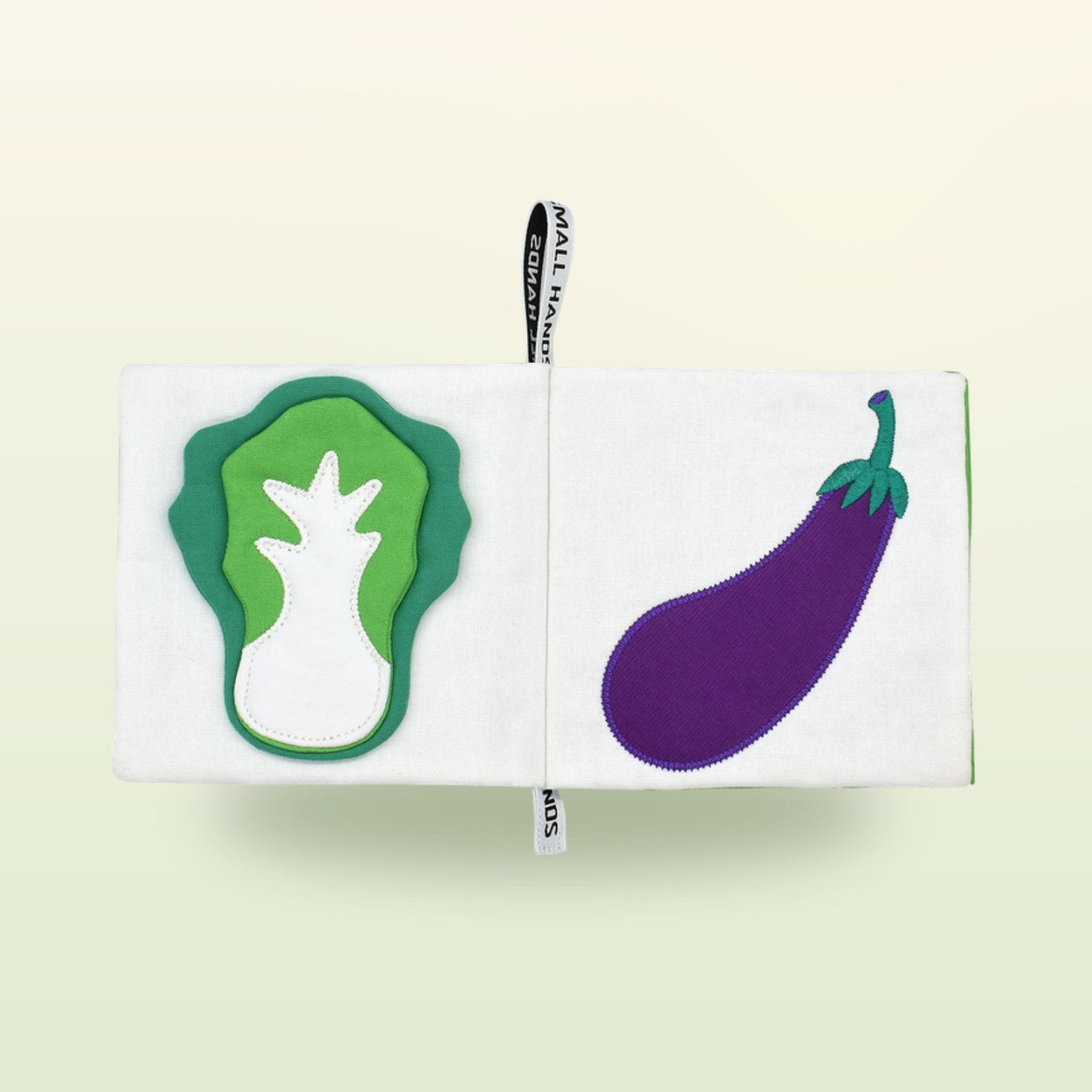 Small Hands Gemüse Montessori Stoffbuch Doppelseite mit Kohl und Aubergine auf sanftem Wiesengrün-Hintergrund – ab 1 Jahr