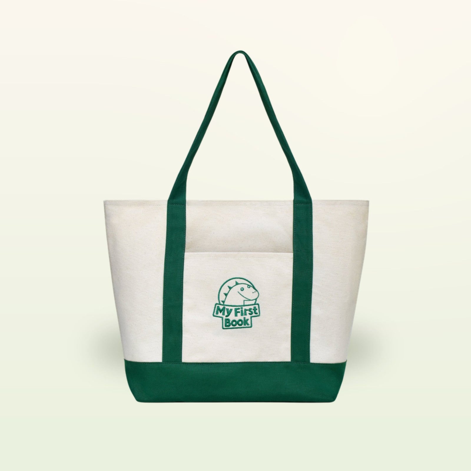 My First Book Tragetasche – cremefarbene Stofftasche mit grünen Henkeln, Vorderansicht auf sanftem Creme-Hintergrund