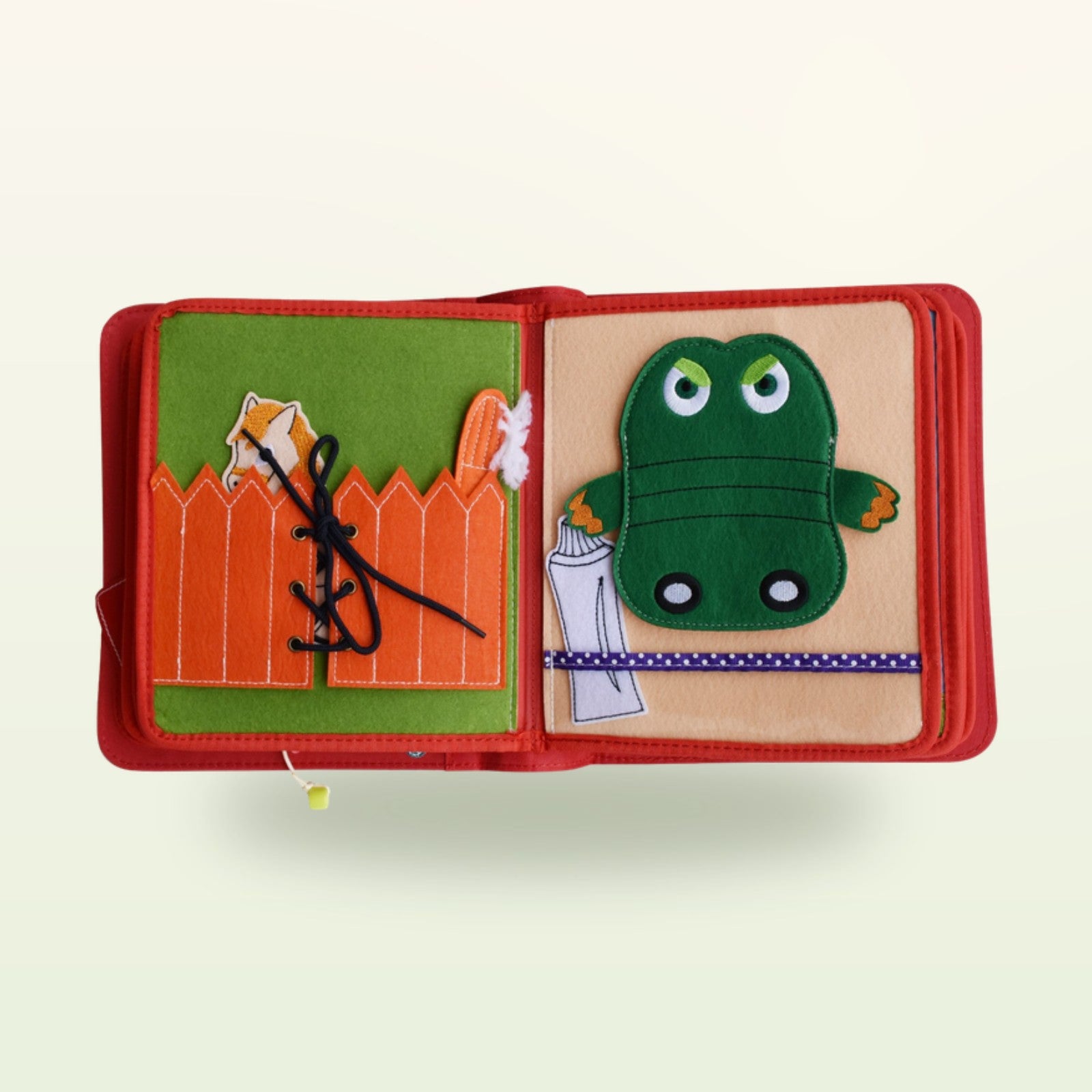 Zirkusabenteuer Quiet Book Doppelseite mit orangem Zaun zum Schnüren und grünem Krokodil zum Zähneputzen auf sanftem cremefarbenem Hintergrund – ab 3 Jahren
