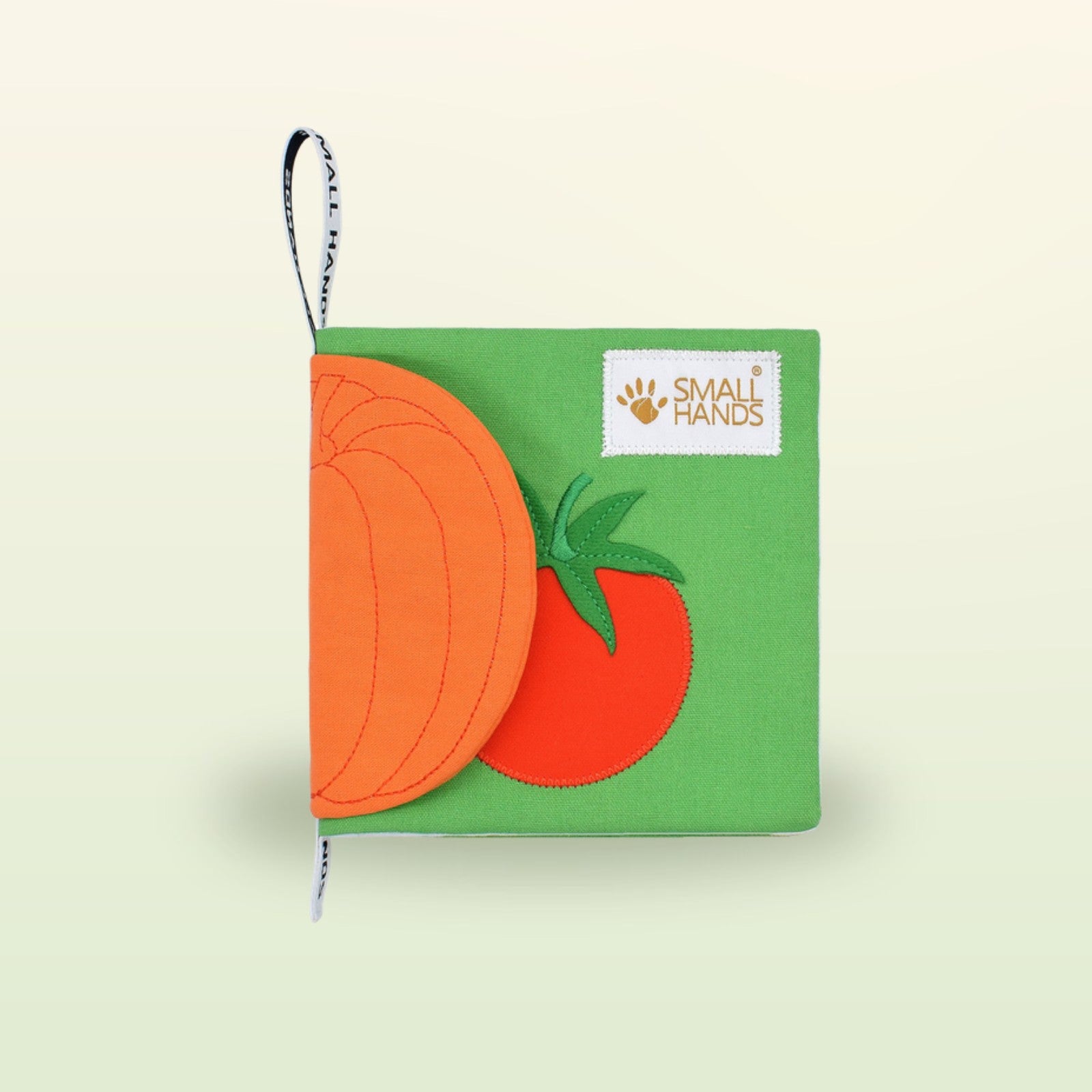 Small Hands Gemüse Montessori Stoffbuch Cover Schrägansicht auf sanftem Wiesengrün-Hintergrund – ab 1 Jahr