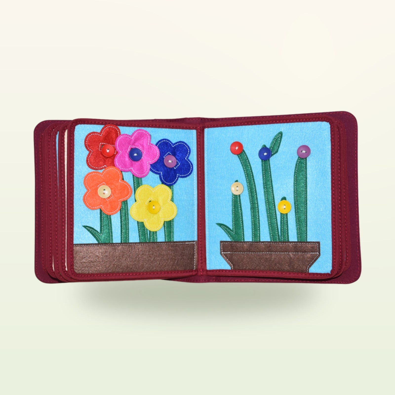 Mein Alltag Quiet Book Blumen-Doppelseite mit bunten Filzblumen zum Anknöpfen an die grünen Stängel auf sanftem cremefarbenem Hintergrund – ab 1 Jahr