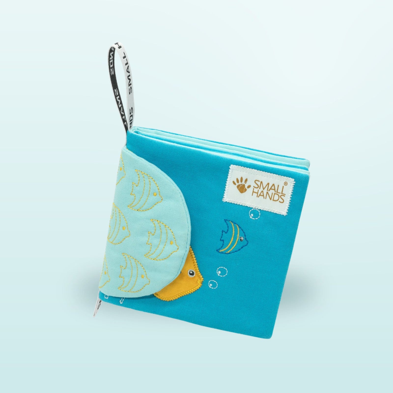 Small Hands Meeresbewohner Montessori Stoffbuch stehend mit Aufhängeschlaufe auf sanftem Unterwasser-Blau-Hintergrund – ab 1 Jahr